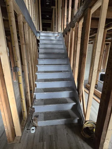 a view of staircase with wooden floor and white walls