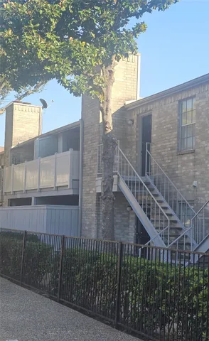 a view of a house with a tree and wooden fence