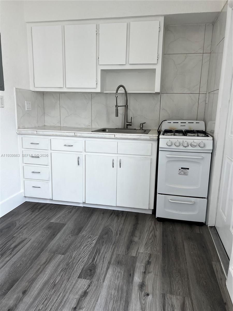 650 83rd Street, Unit 1 Miami Beach, FL 33141 - Photo 22 of 37 a kitchen with cabinets wooden floor appliances and a sink