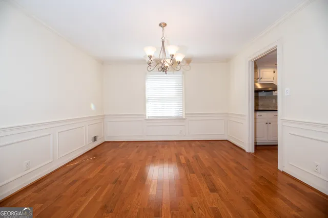 a view of a room with wooden floor electronic appliances and windows