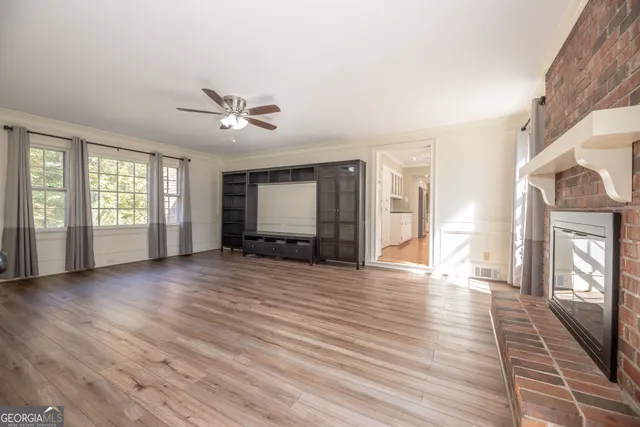 a view of an empty room with a window and wooden floor