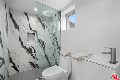 a white toilet sitting next to a bathroom sink and a mirror