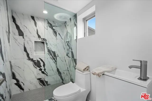 a white toilet sitting next to a bathroom sink and a mirror