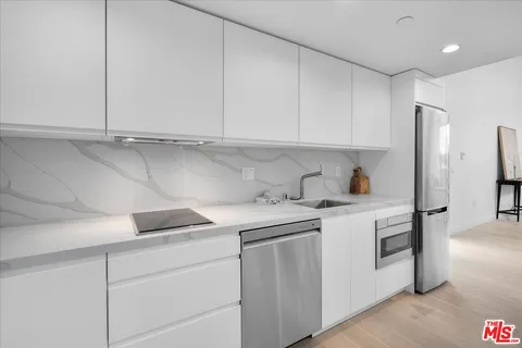 a kitchen with stainless steel appliances granite countertop white cabinets and a sink