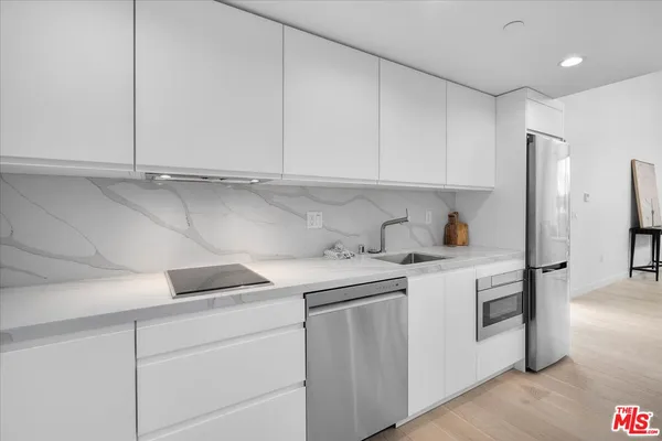 a kitchen with stainless steel appliances granite countertop white cabinets and a sink