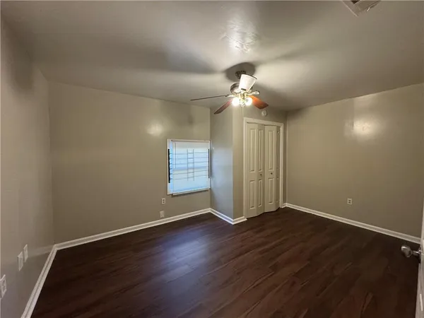 an empty room with wooden floor chandelier fan and windows