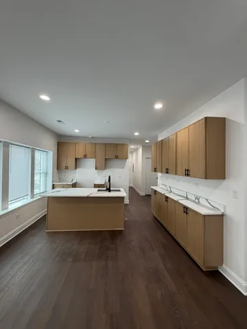 a large living room with stainless steel appliances kitchen island granite countertop a large window and a couch