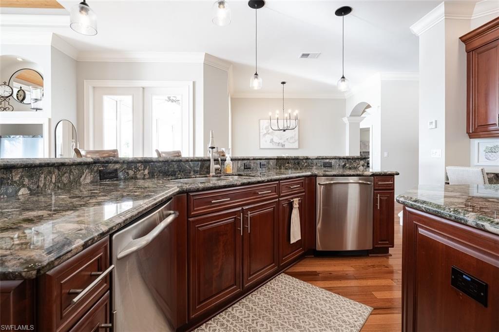 1942 Kingfish Road Naples, FL 34102 - Photo 16 of 43 a kitchen with stainless steel appliances granite countertop a sink a stove and a wooden floors