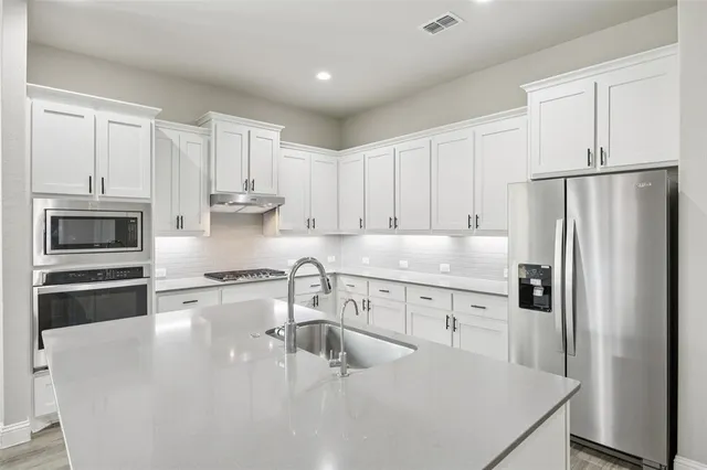 a kitchen with stainless steel appliances a refrigerator sink and microwave