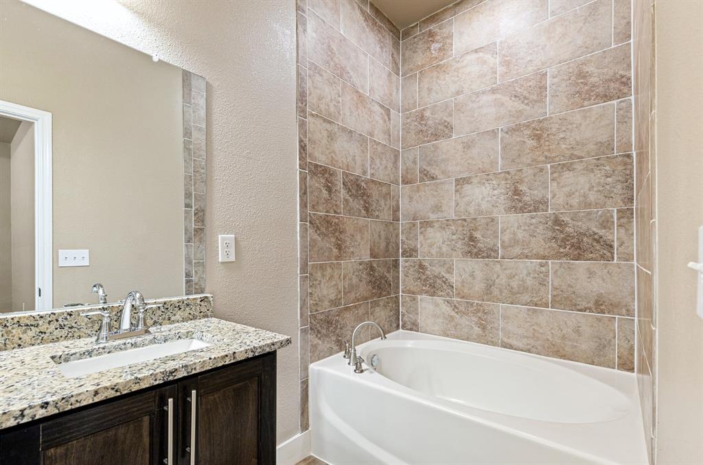 413 Henderson Street Bonham, TX 75418 - Photo 22 of 27 a bathroom with a granite countertop bathtub sink vanity and shower