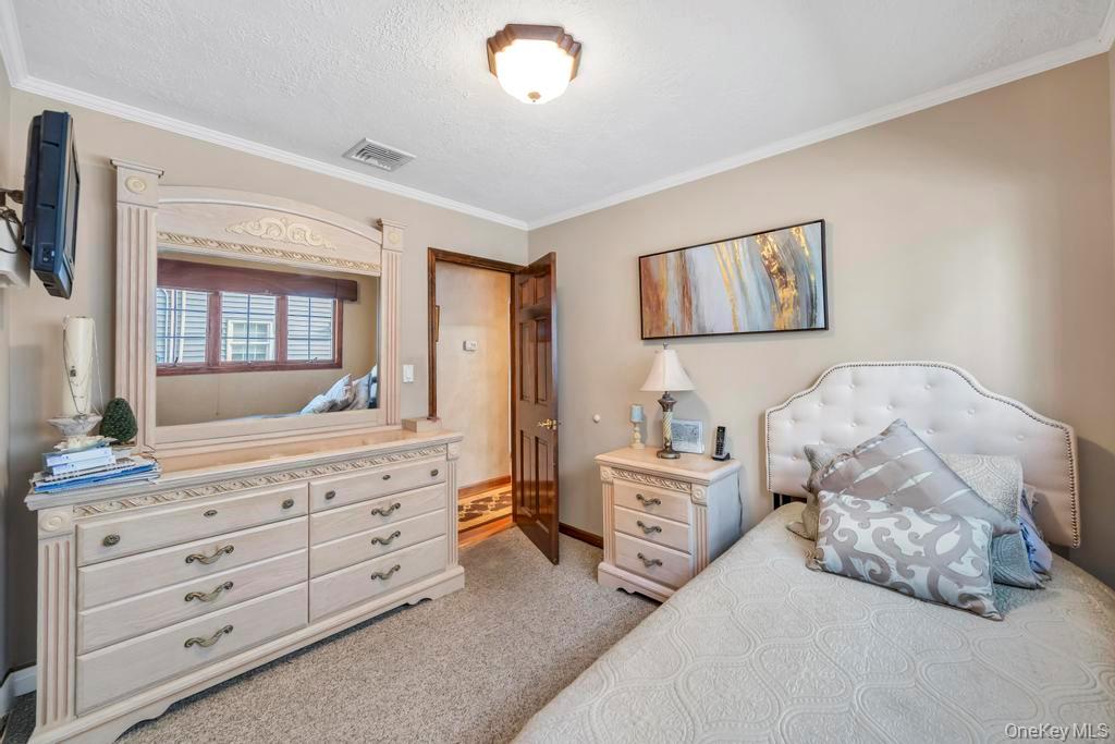 60 Essex Road Bethpage, NY 11714 - Photo 12 of 21 Bedroom featuring light carpet, crown molding, and a textured ceiling