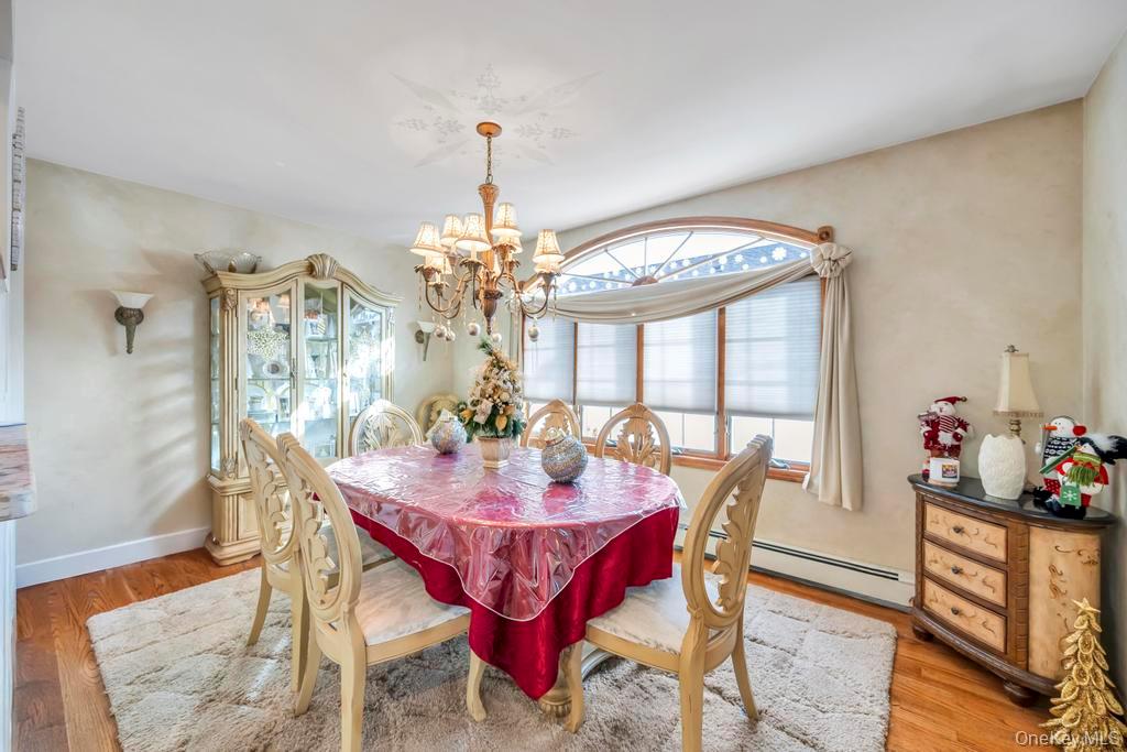 60 Essex Road Bethpage, NY 11714 - Photo 5 of 21 Dining space with a baseboard radiator, wood finished floors, and a chandelier