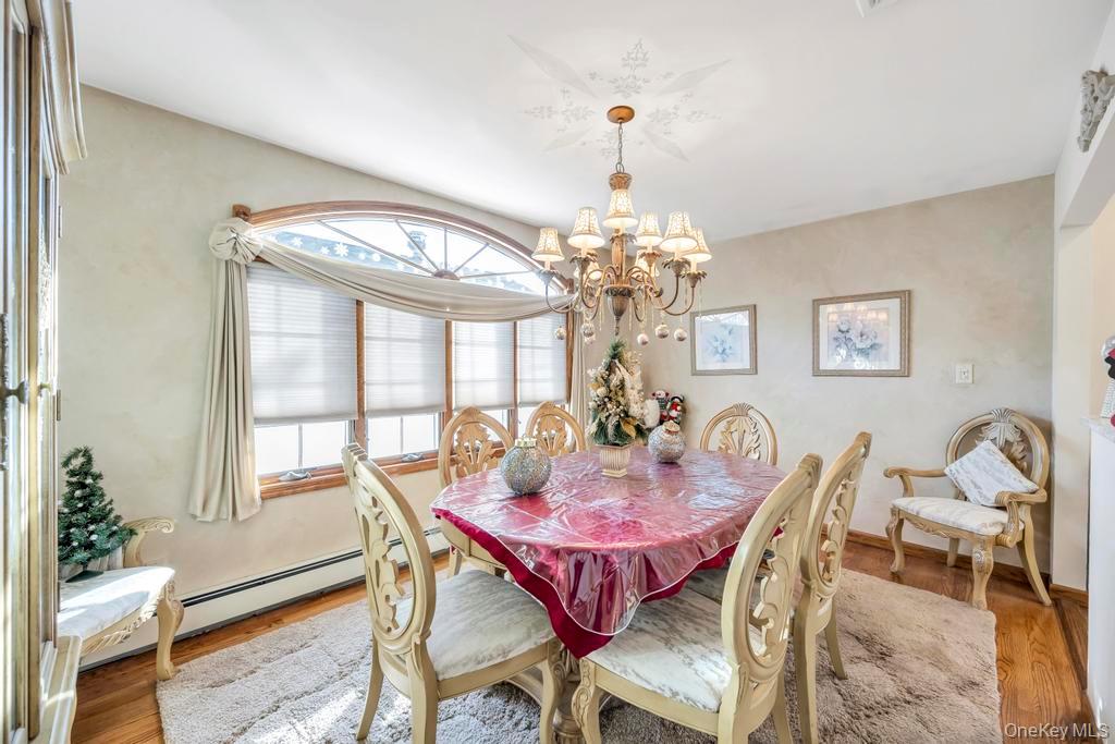 60 Essex Road Bethpage, NY 11714 - Photo 6 of 21 Dining area with a chandelier, wood finished floors, and a baseboard heating unit