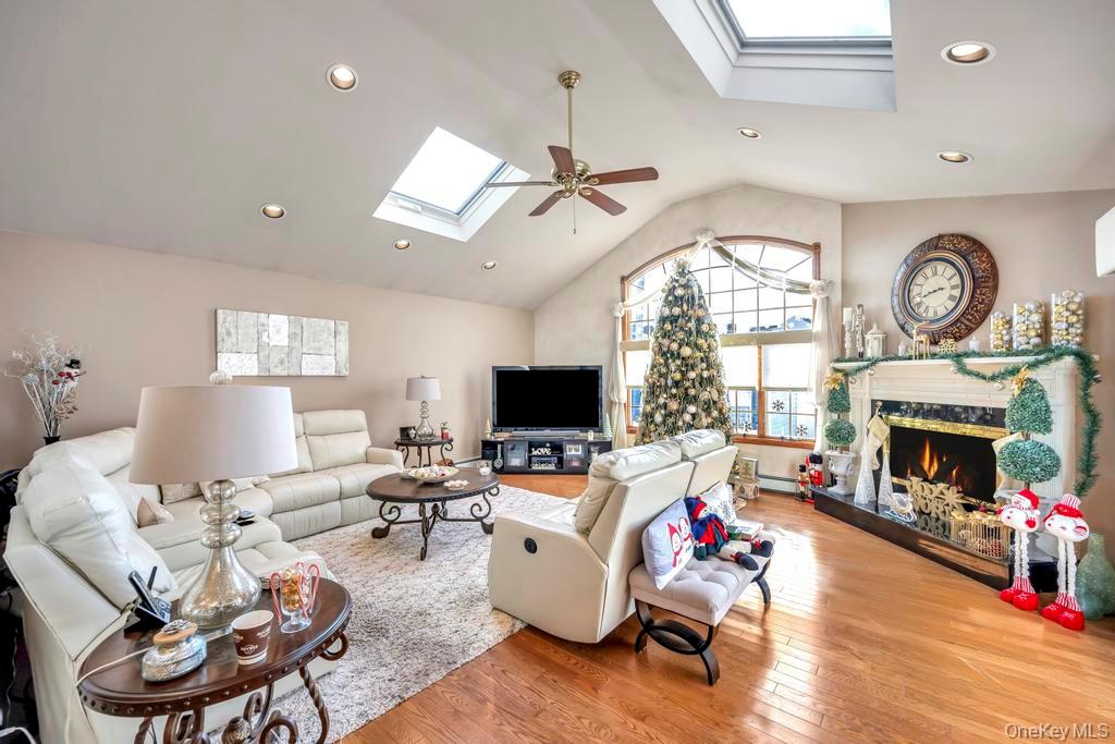 60 Essex Road Bethpage, NY 11714 - Photo 7 of 21 Living area with a skylight, wood-type flooring, a high end fireplace, recessed lighting, and high vaulted ceiling