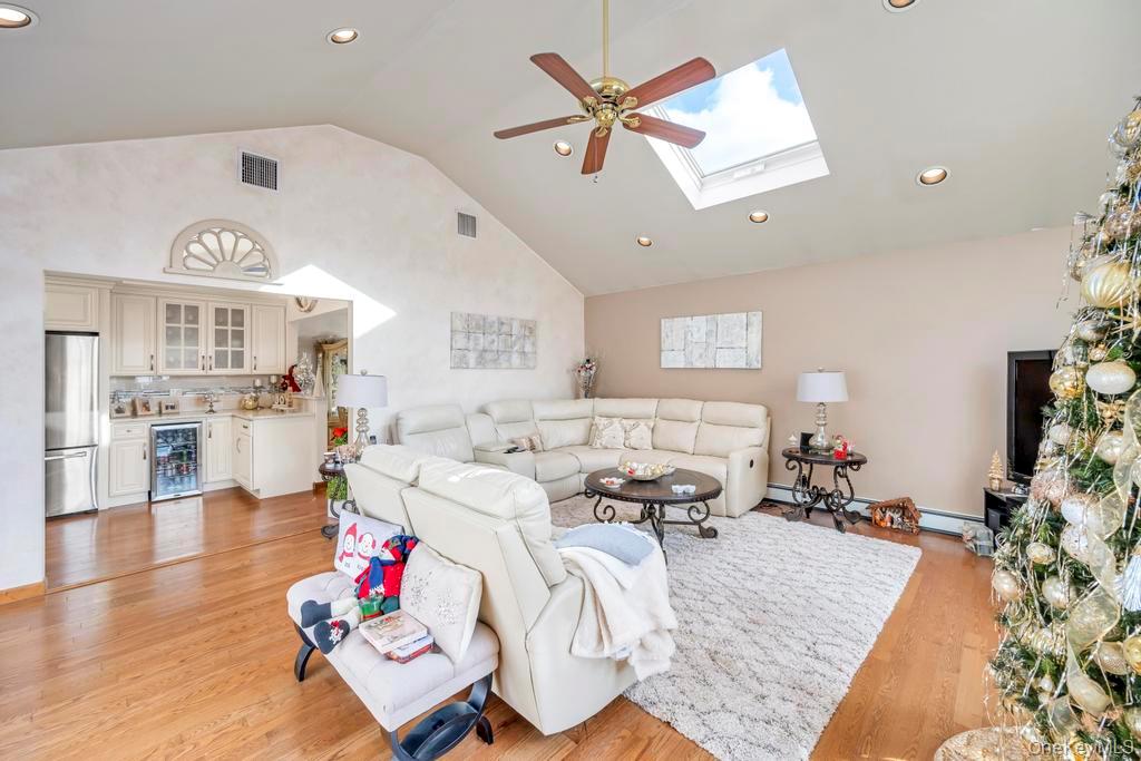 60 Essex Road Bethpage, NY 11714 - Photo 8 of 21 Living area with recessed lighting, wine cooler, light wood-style flooring, high vaulted ceiling, and a skylight