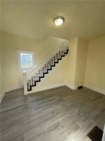 a view of an empty room with wooden floor and stairs