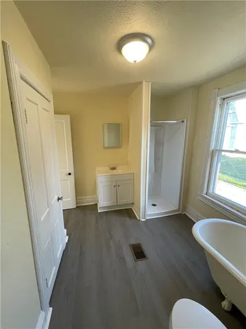 a view of an empty room with a window and wooden floor