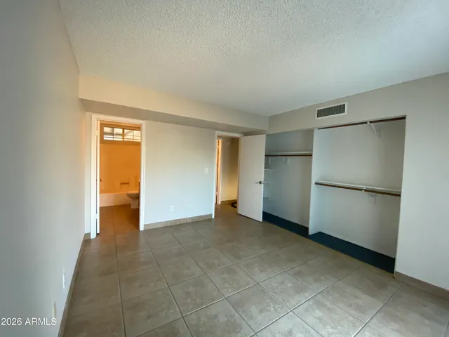 a view of an empty room with closet and a window