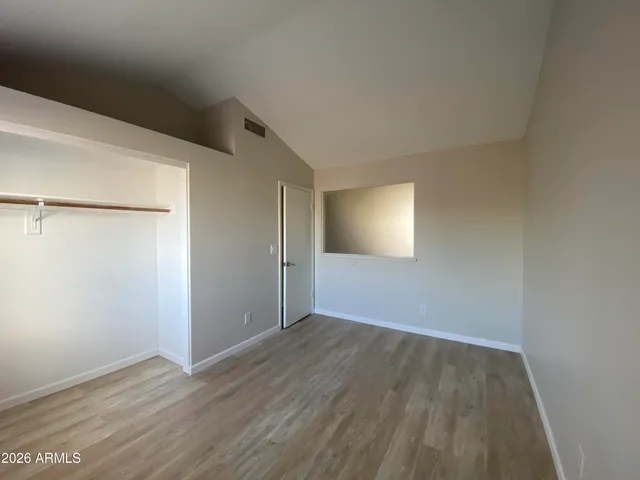 a view of an empty room with wooden floor and closet