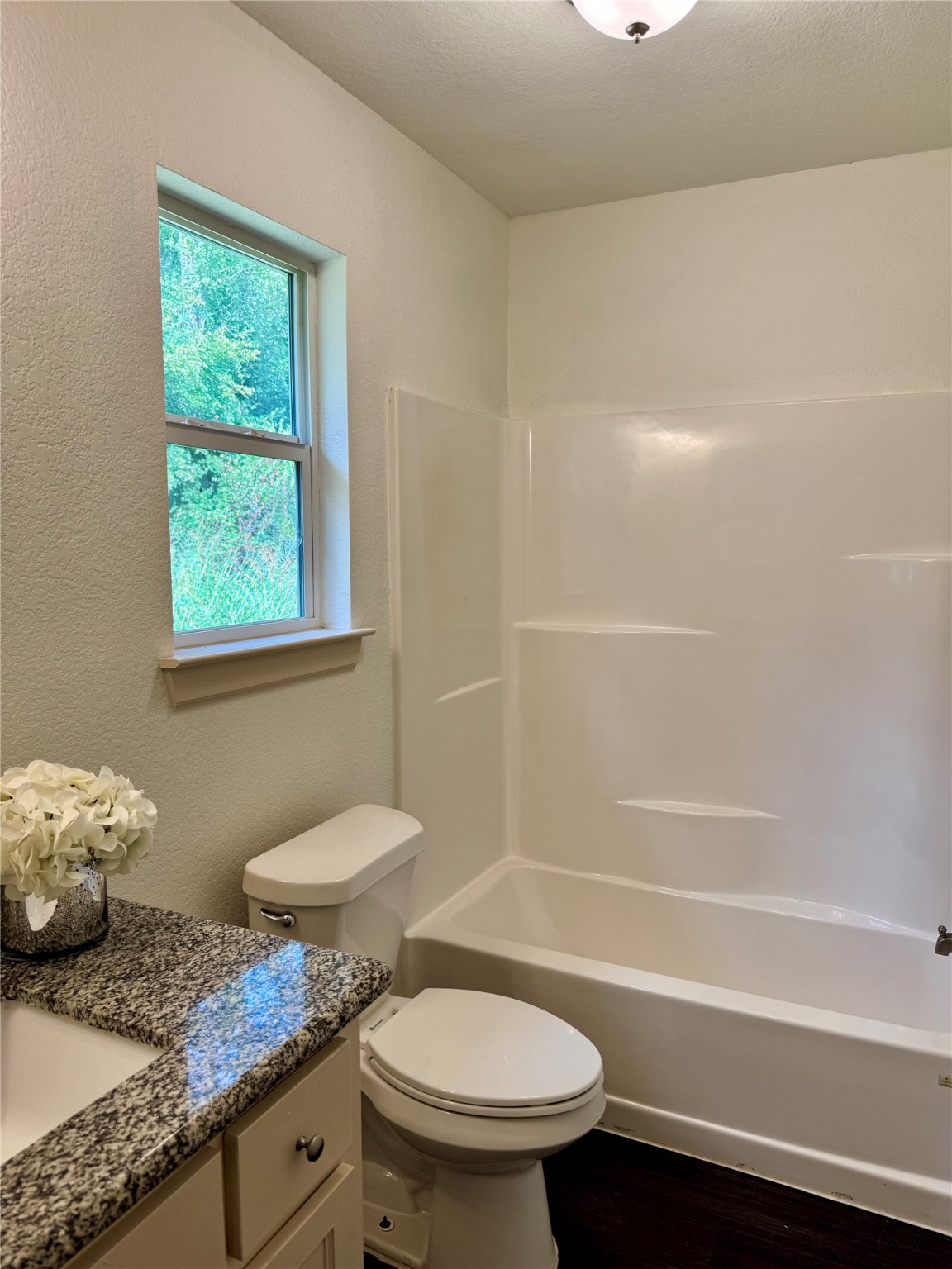 624 Luke Street, Unit A Dayton, TX 77535 - Photo 19 of 20 a bathroom with a granite countertop toilet a sink and a bathtub