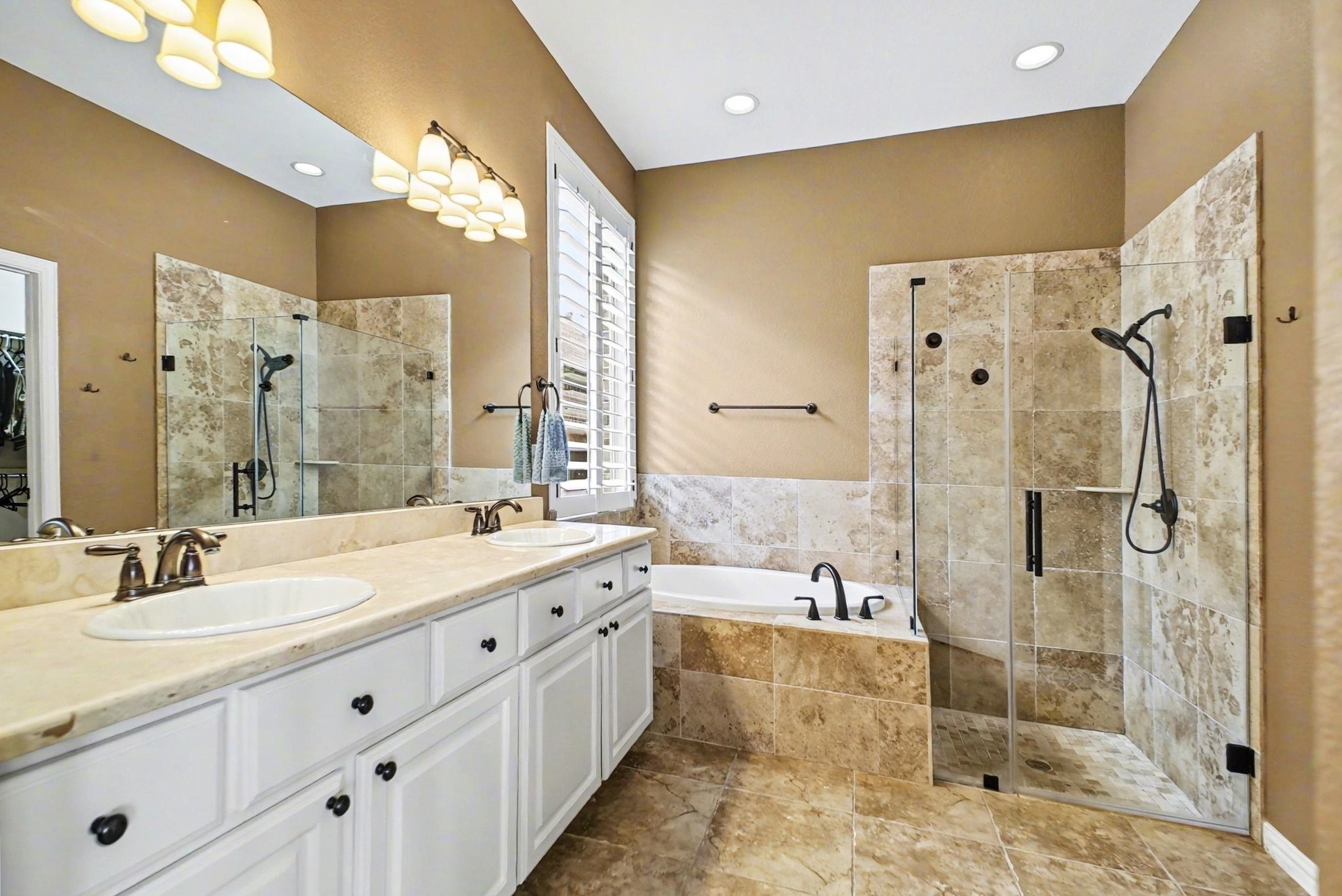 8210 Thunder Ridge Way Missouri City, TX 77459 - Photo 25 of 42 Luxurious primary bathroom featuring a dual vanity, deep soaking tub, and sleek glass shower. Conveniently, a walk-in closet is located to the right.