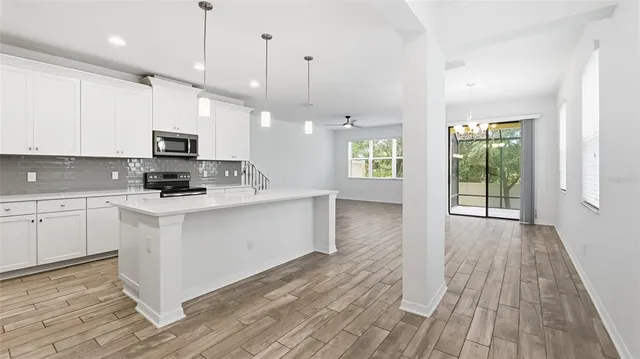 a large kitchen with cabinets wooden floor and stainless steel appliances