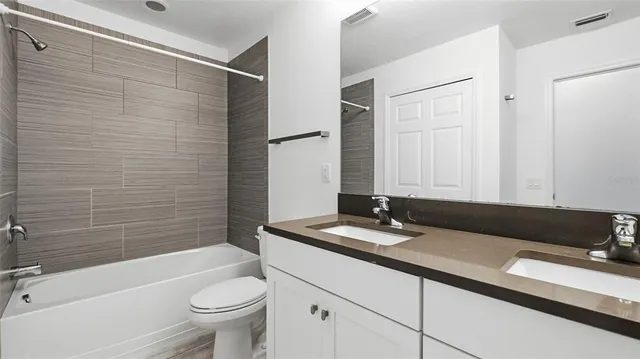 a bathroom with a granite countertop bathtub sink vanity mirror and toilet