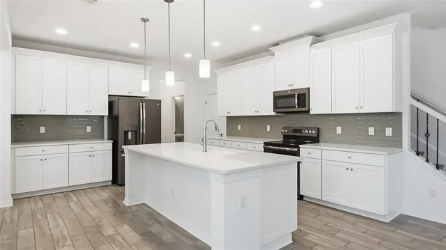 a kitchen with stainless steel appliances a refrigerator sink and white cabinets