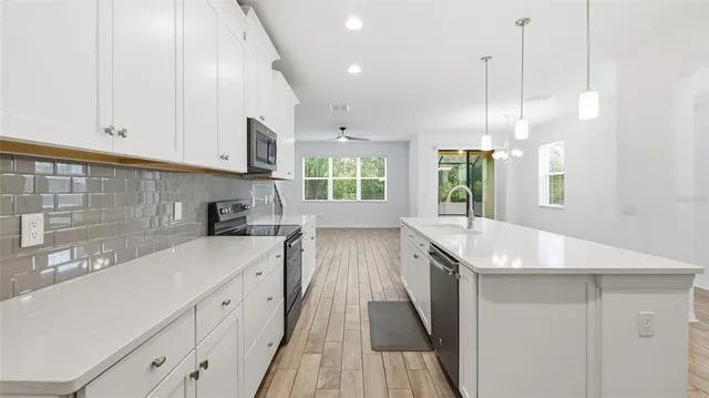 a kitchen with granite countertop a sink a counter space appliances and cabinets