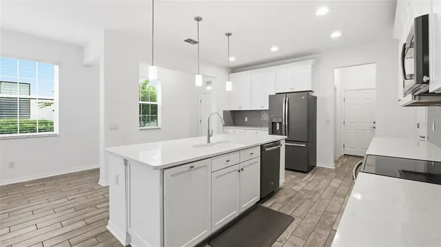 a kitchen with a refrigerator a sink and dishwasher with wooden floor