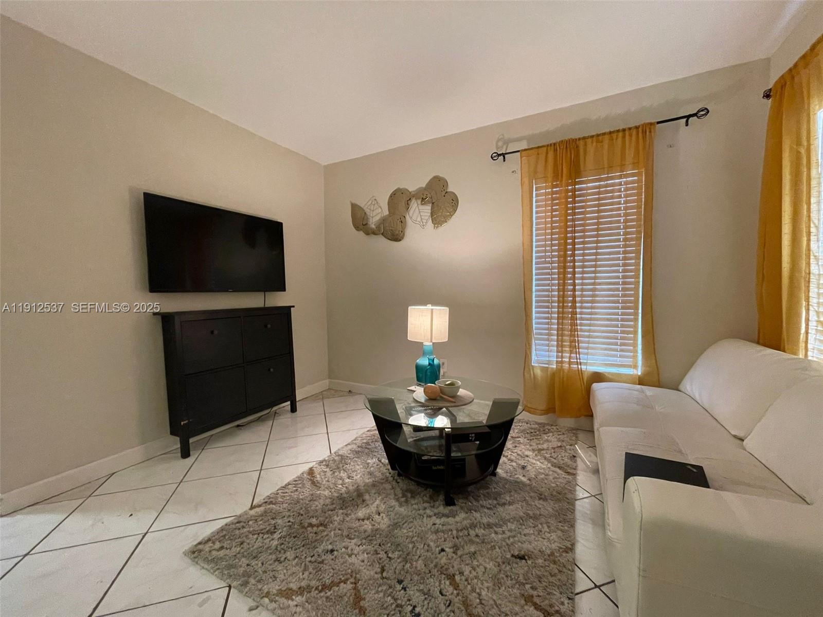 55 Northwest 69th Street, Unit E Miami, FL 33150 - Photo 3 of 7 a living room with furniture and a flat screen tv