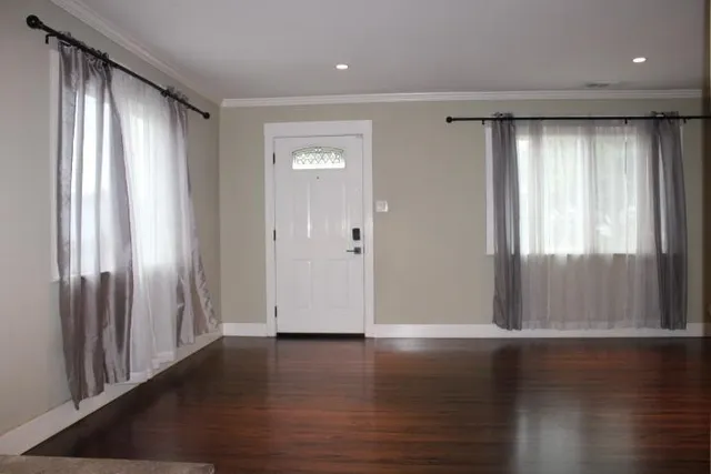 an empty room with wooden floor and windows
