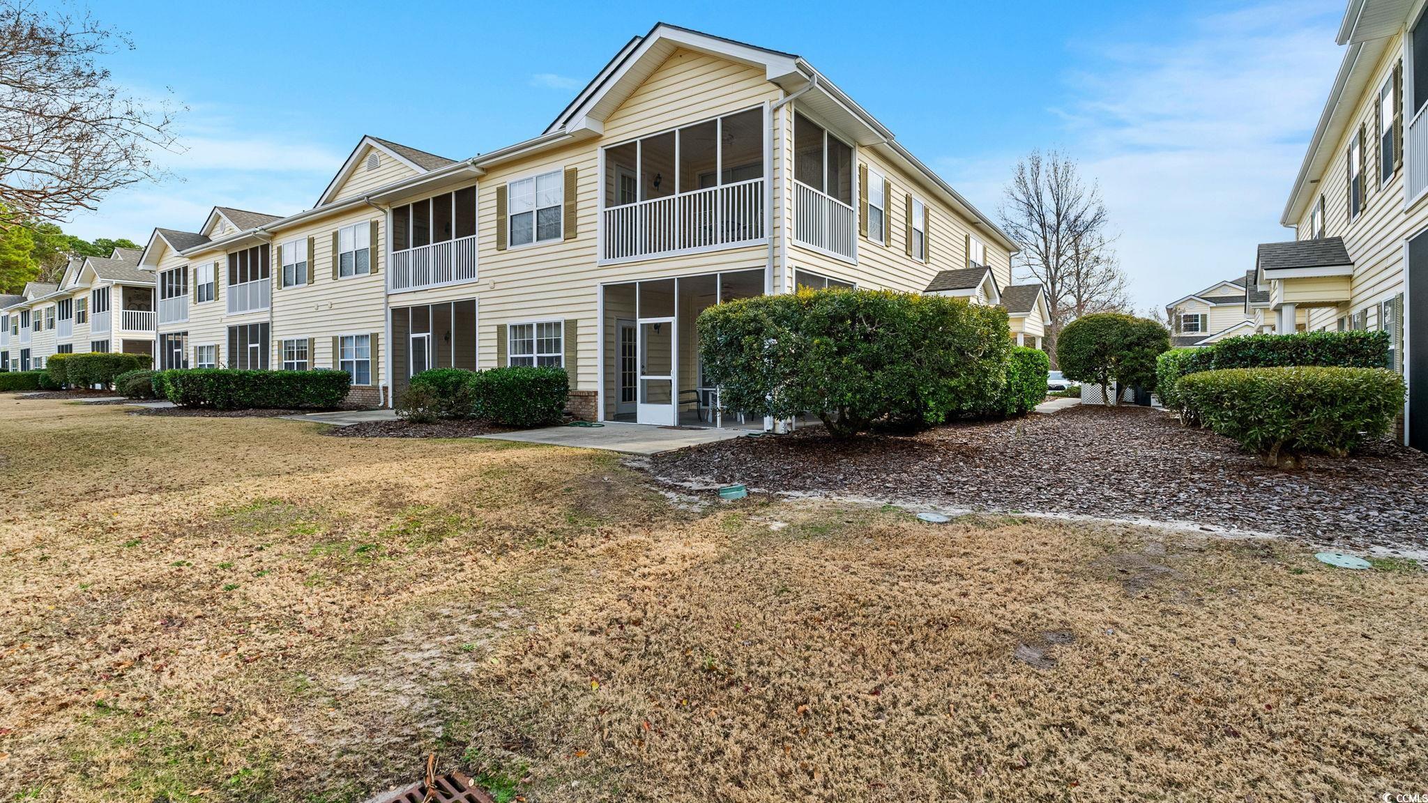View of front of home with a sunroom, a front lawn, and a balcony