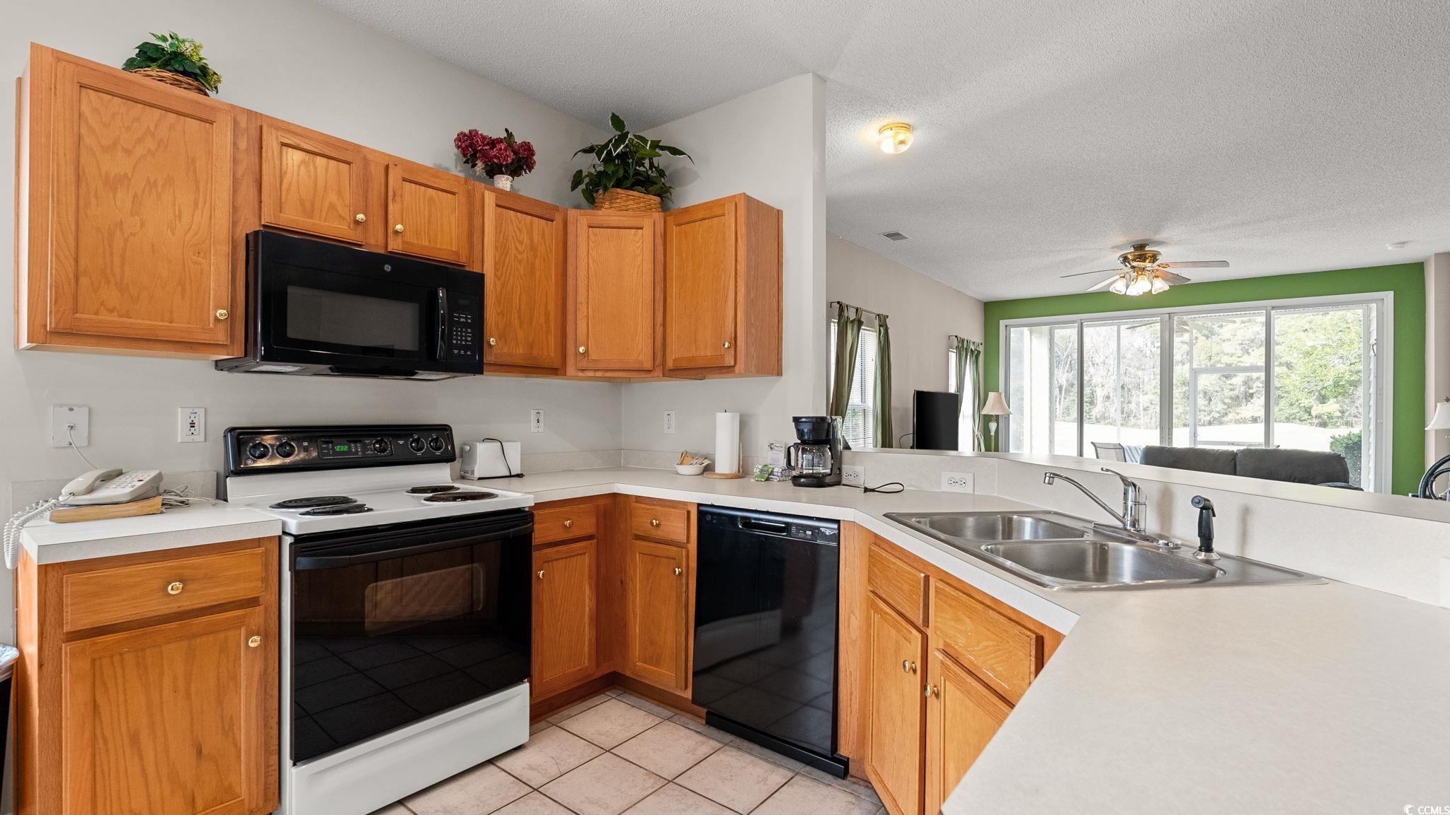 4431 Montrose Lane, Unit A Myrtle Beach, SC 29579 - Photo 9 of 32 Kitchen featuring black appliances, light countertops, a textured ceiling, light tile patterned floors, and brown cabinets