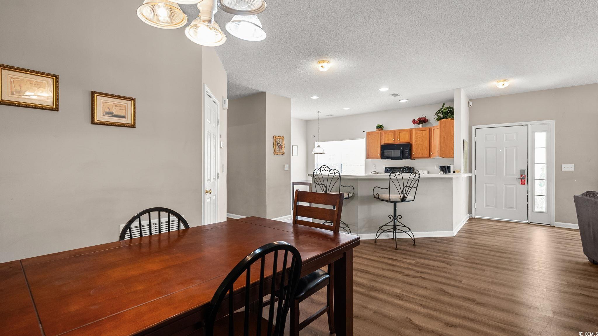4431 Montrose Lane, Unit A Myrtle Beach, SC 29579 - Photo 10 of 32 Dining area featuring a textured ceiling, dark wood-type flooring, and a chandelier