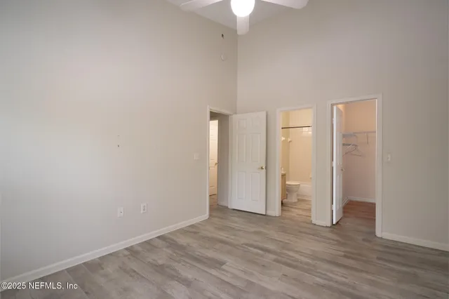 a view of an empty room with wooden floor and a ceiling fan