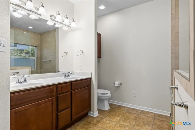 a bathroom with a double vanity sink toilet and a mirror
