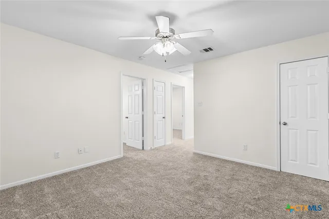 an empty room with a chandelier fan and windows