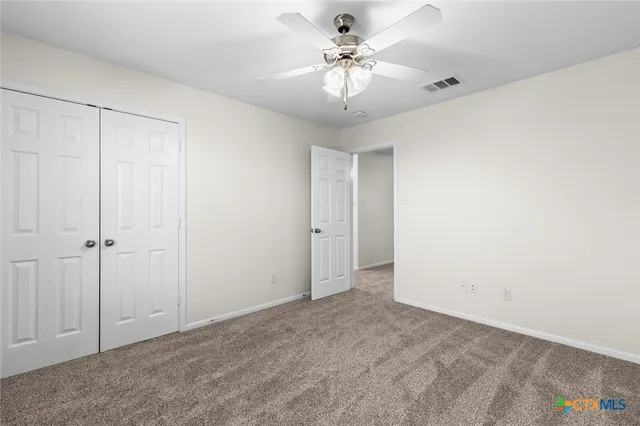 an empty room with a chandelier fan and windows