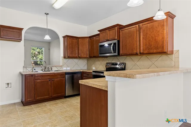 a kitchen with stainless steel appliances granite countertop a sink a stove a microwave and wooden cabinets