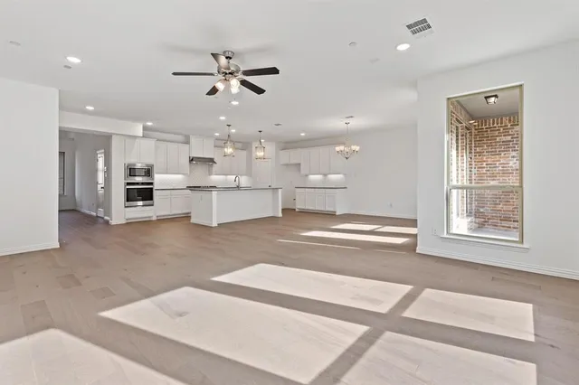 a view of an empty room with a window and a kitchen