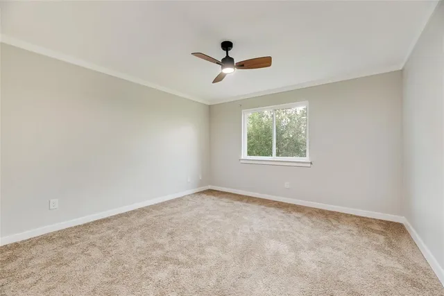 an empty room with windows and ceiling fan