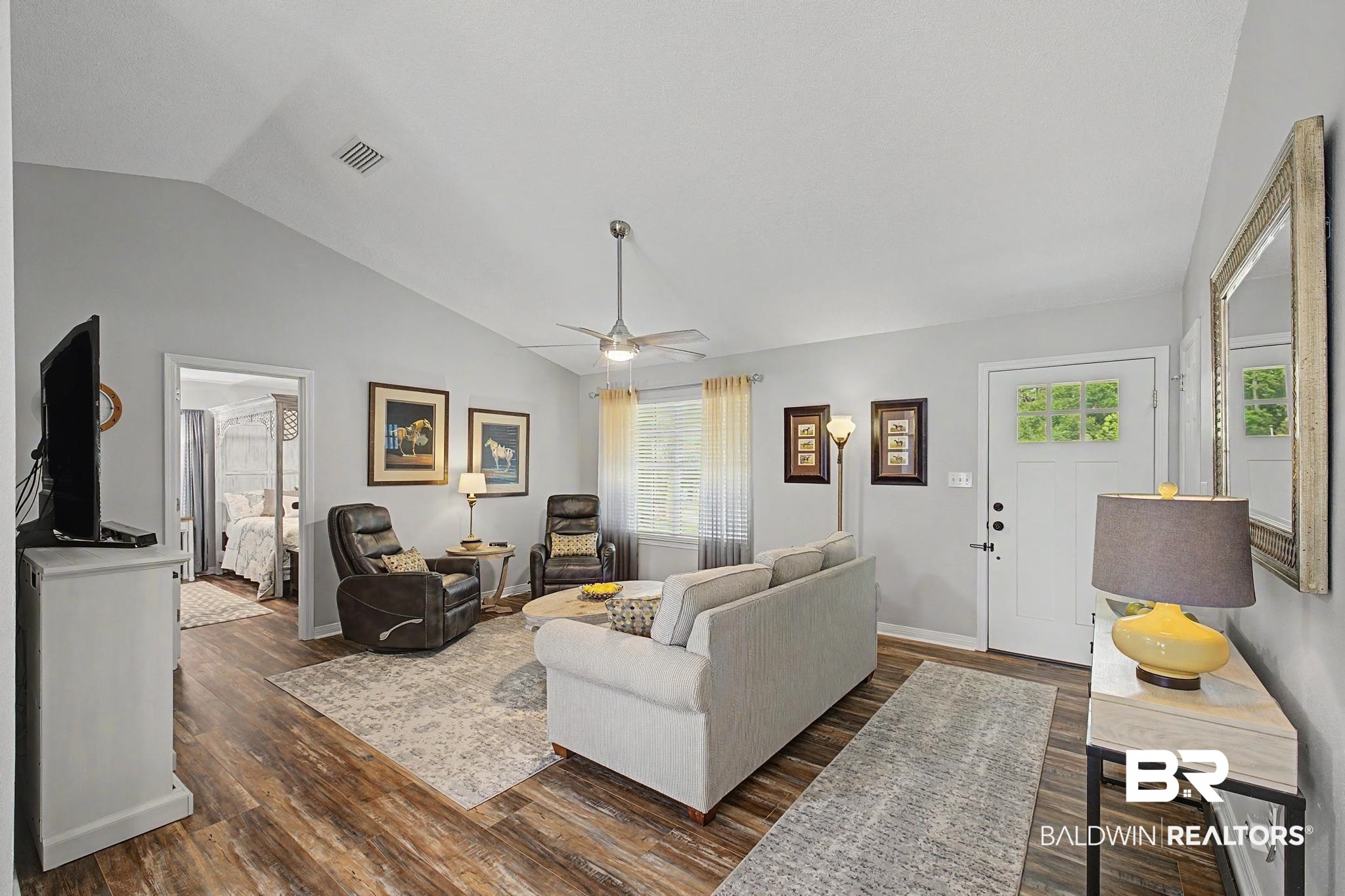 2808 Pine Ridge Drive Lillian, AL 36549 - Photo 10 of 47 Living area with vaulted ceilings, wood-finish flooring, a ceiling fan, and a front entry door featuring a multi-pane window