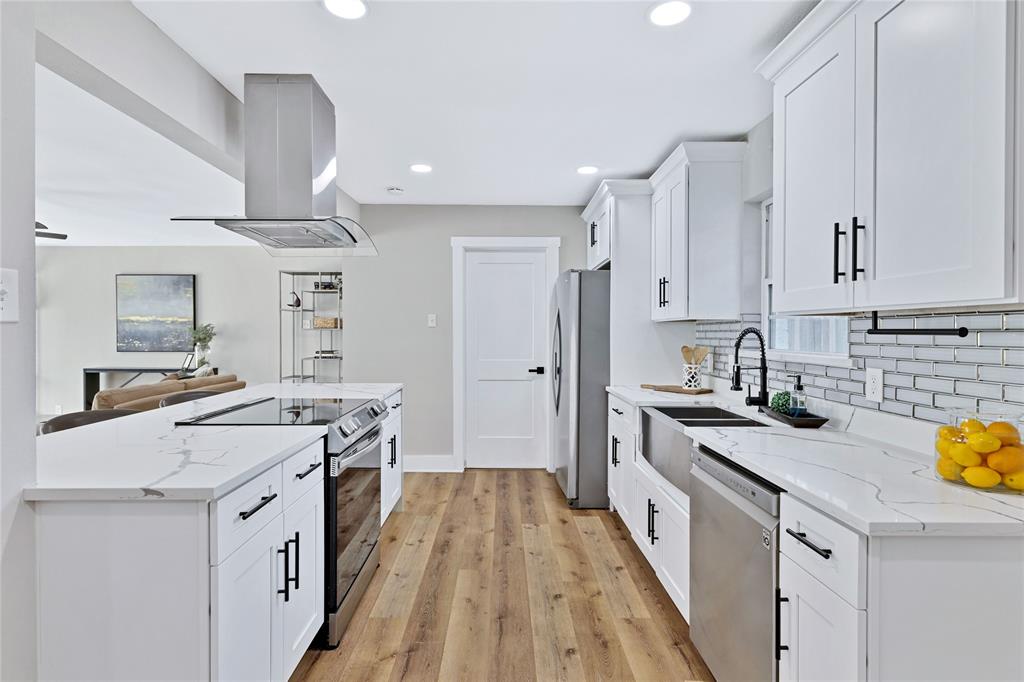 8635 Strathmore Drive Dallas, TX 75238 - Photo 10 of 35 a kitchen with stainless steel appliances a stove a sink dishwasher a refrigerator white cabinets and wooden floor next to a window