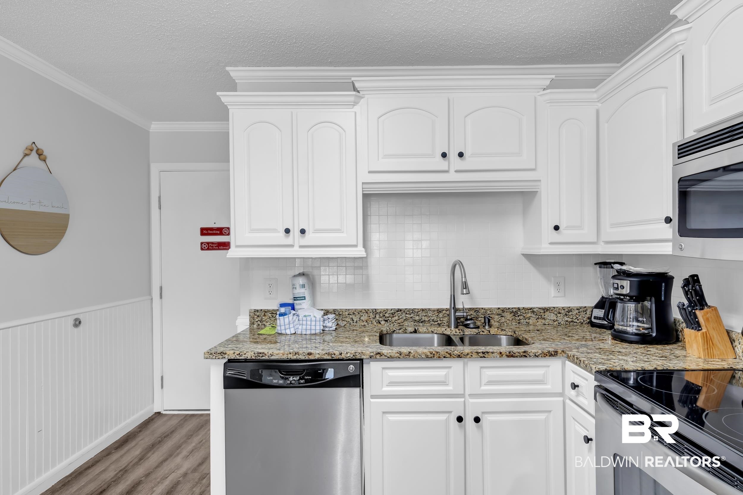 400 Plantation Road, Unit 2118 Gulf Shores, AL 36542 - Photo 10 of 59 Kitchen featuring white cabinetry, granite-style countertops, stainless steel appliances, a double basin sink, and a tiled backsplash