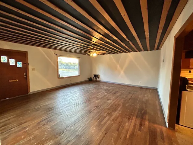 a view of a hallway with wooden floor and a livingroom with furniture