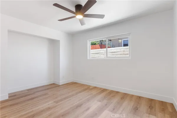 an empty room with a window and a fan