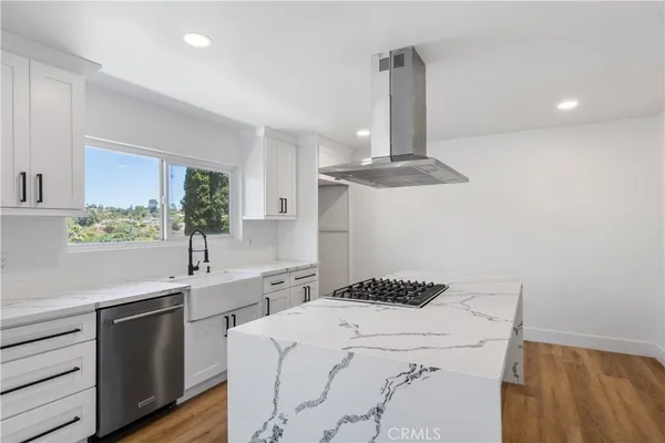 a kitchen with a sink dishwasher a stove and white cabinets with wooden floor