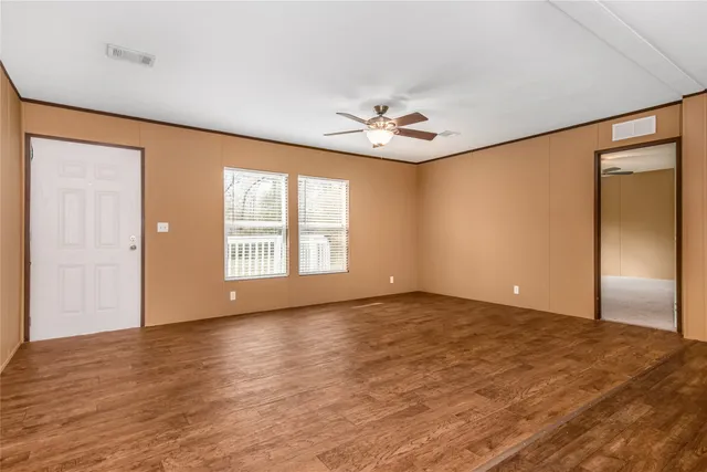 a view of an empty room with a window and wooden floor