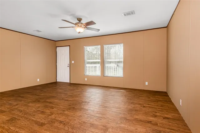a view of an empty room with a window and wooden floor